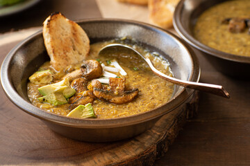 Vegan cream of mushroom soup on wooden table along with toasted bread and avocado
