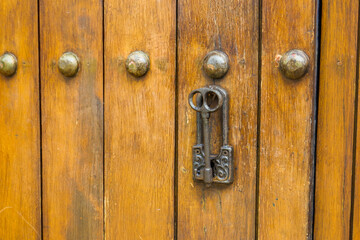 Close up of old Key in wooden door at home, Brown Wood Front Door with Ornate Brass Skeleton...
