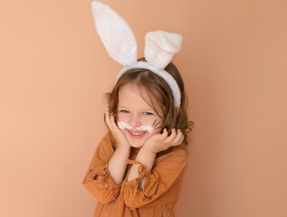 A sweet smiling little girl dressed up as an Easter bunny with a painted face