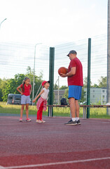 The father scolds the child for educational purposes. Naughty girl argues with her father during basketball break