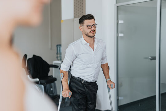 A confident businessman using crutches navigates through a modern office environment, exemplifying determination. Ideal for themes of disability awareness and diverse workplace inclusion.