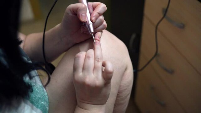 woman hands using a nail buffer on her nails after cuticle removal, showcasing a professional manicure process in slow motion