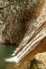A high waterfall in a green forest with rocks