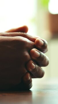 Person, hands and waiting with patience for health, therapy or counselling for loss at home. Closeup, grief or faith in god with feeling, care or pray for emotion, sensory or touch on table at house