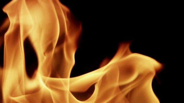 Beautiful dancing fire, the surface is ablaze. Lots of fire. Close-up immersion in the flames. The camera passes through the fire. Burning tongues of flame on a black backdrop in slow motion. 4K.