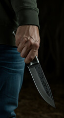 Menacing Grip: Hand Holding Forged Knife in Dark, Dramatic Lighting - Sharp Blade, Danger, and Mystery