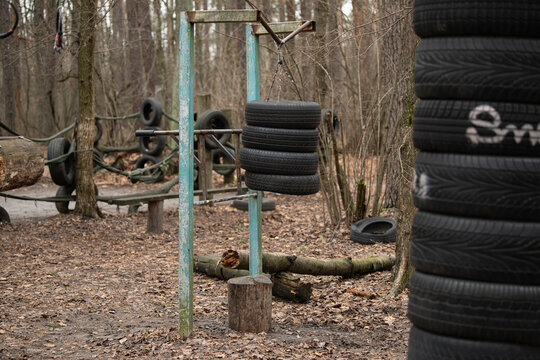 This outdoor sports ground features various tire setups designed for fitness training, surrounded by trees and natural elements. Ideal for robust exercise and skill development