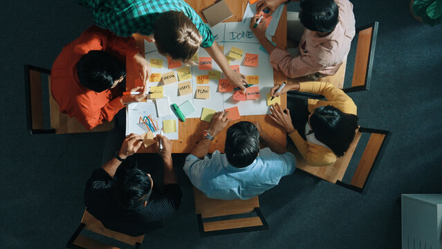 Top view of people writing and making scrum task board while writing marketing and planning strategy at colorful sticky notes. Smart team manage work performance by using kanaban board. Convocation.