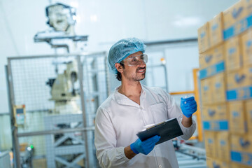 Inspector monitoring packaged goods near an automated robotic system in a factory. Focus on quality...