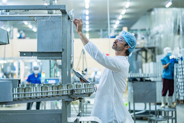 Engineer supervising the food production process in a high tech manufacturing plant inspecting...