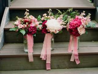 Beautiful floral arrangements with pink ribbons displayed on wooden steps outdoors at a garden venue