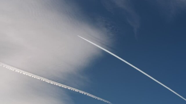An Airplane is majestically crossing the Sky, leaving behind a beautiful, white contrail in its path
