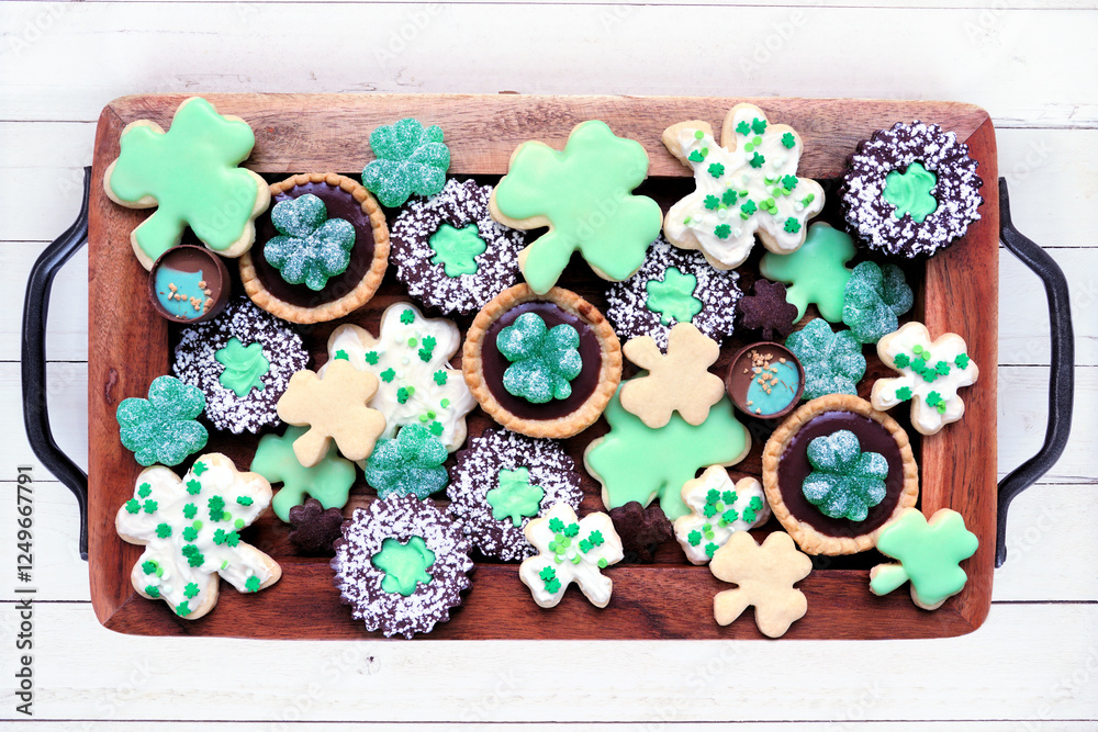Poster st patricks day shamrock dessert board. green cookies and sweets. overhead view on a rustic wood bac