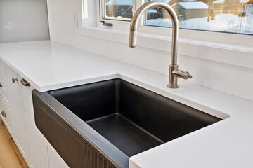 Black sink with a silver faucet sits on a white countertop