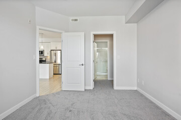 White bedroom with a door leading to a kitchen