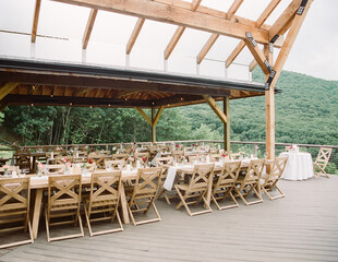 Beautiful outdoor dining setup with wooden tables and scenic mountain view at a rustic venue for a special event
