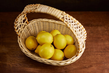 lemons in a beautiful wicker basket on a wooden background, close-up, top view