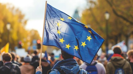 Man holding blue flag with yellow stars in front of crowd