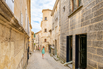 Obraz premium A young woman walks down a cobblestone lane in the medieval center of a French Village.