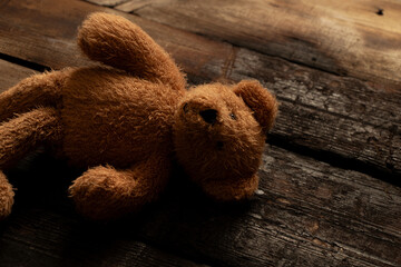 Brown soft baby teddy bear lying abandoned on the floor