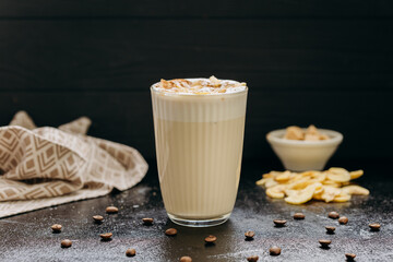 Creamy latte with whipped foam, dried apple slices, and cinnamon, served on a dark textured surface