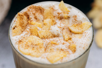 Creamy latte with whipped foam, dried apple slices, and cinnamon, served on a dark textured surface