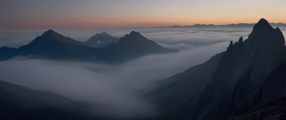A dramatic image of thick mist hovering over mountains at dawn where the peaks shimmer faintly through shrouded layers of mystery