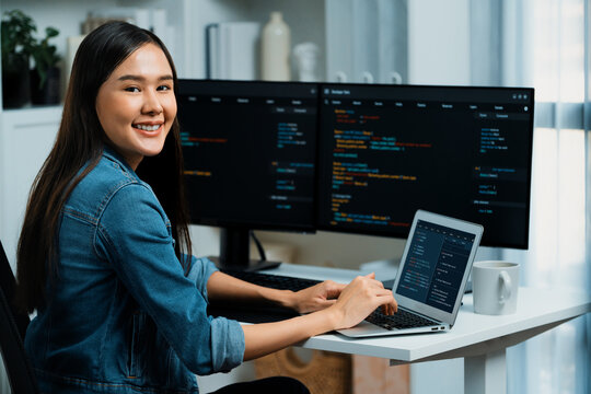 Young Asian in IT developer looking at camera to present with online information on pc with coding program data application, wearing jeans shirt. surround by safety analysis two screens. Stratagem.