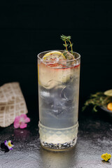 Refreshing citrus-infused cocktail with ice and thyme garnish in a stylish glass, perfect for summer