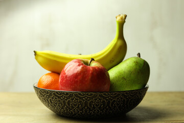 Still life of fresh fruits in a bowl on wooden table, selective focus