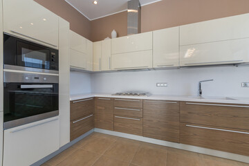 Elegant kitchen design. The kitchen set with built-in appliances is decorated with white and wooden panels.