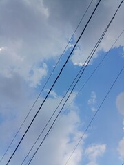 Electrical Cables Crossing a Cloudy Blue Sky