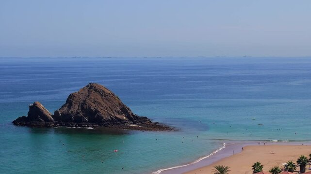 Snoopy Island in Fujairah, UAE. Aerial view of the beach with turquoise waters, a rocky island and a resort nearby