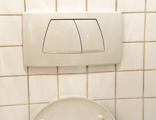 Dual flush toilet buttons on tiled wall for water efficiency