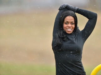 Attractive young African American woman stretches in black leggings and long sleeve shirt (winter)