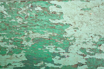 Weathered green paint reveals layers of history on old wooden surface