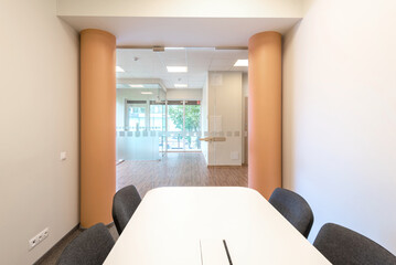 Modern Office Interior with Glass Partitions and Minimalist Furniture Design. A bright and modern office setup featuring a glass-walled meeting room with minimalist furniture.