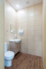 Modern Office Restroom Interior with Wooden Details and Sink Basin. A clean and modern restroom featuring a toilet, sink basin, and wooden decor