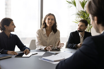 Young confident businesswoman providing update on progress of project she leading, presenting new...
