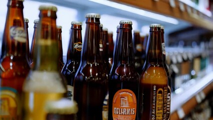 Assorted craft beer bottles on display in refrigerator aisle of supermarket