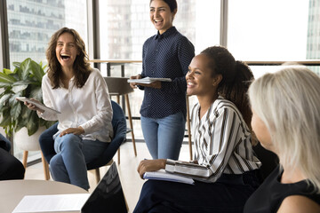 Group of people gathered in office, engaged in lively and cheerful discussion, laughing heartily,...