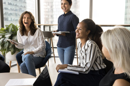 Group of people gathered in office, engaged in lively and cheerful discussion, laughing heartily, enjoying moments of camaraderie and positive interaction, during meeting or a brainstorming session