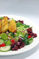 Sliced baked chicken breast on Mediterranean salad with beets and pistachios dinner plate