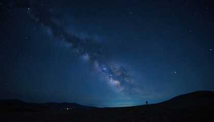 Fototapeta premium Person stands on hilltop observing magnificent starry night sky filled with glowing galaxy. Night sky vibrant with bright stars. Dark landscape. Starry night. Beautiful view. Outer space. Celestial