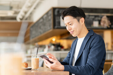 カフェでスマホを見るミドルの男性