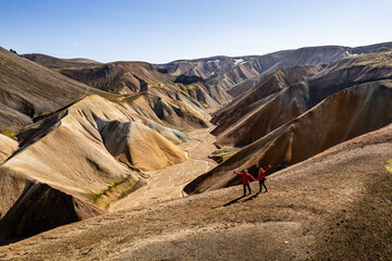 Couple hiking in stunning, rugged, and colorful mountainous Landmannalaugar terrain in Iceland...