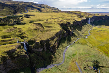 A aerial view Gljufrabui and Seljalandsfoss waterfall in Iceland plunges over the edge of green cliffs, surrounded by stunning countryside. The serene landscape captures beauty of untouched nature
