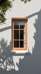 Elegant wooden-framed window on a smooth white wall with dramatic tree shadows, illustrating a balance between architecture, nature, and light in a modern setting

