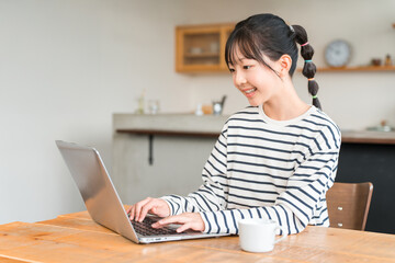 自宅のリビング・スタディコーナーでパソコンを使う小学生・中学生の女の子
