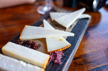 Tasting of Spanish cheeses made on Canary islands, goat cheese, smoked and triangles of manchego curado cheese on wooden plank